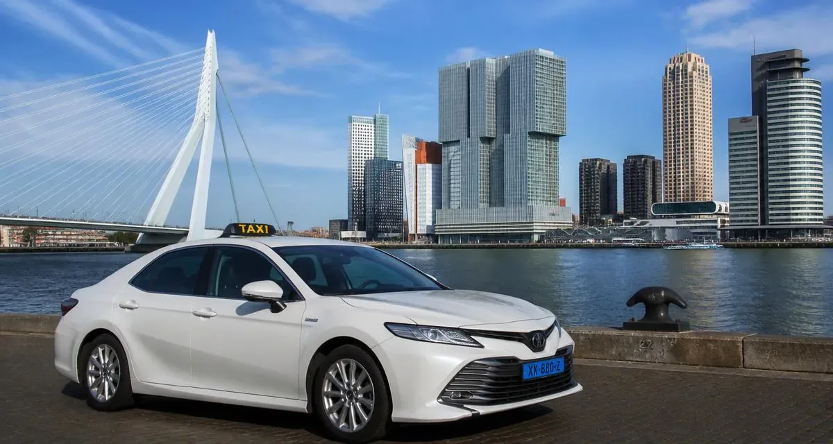 Witte taxi aan de Maas met de Erasmusbrug en de skyline van Rotterdam op de achtergrond