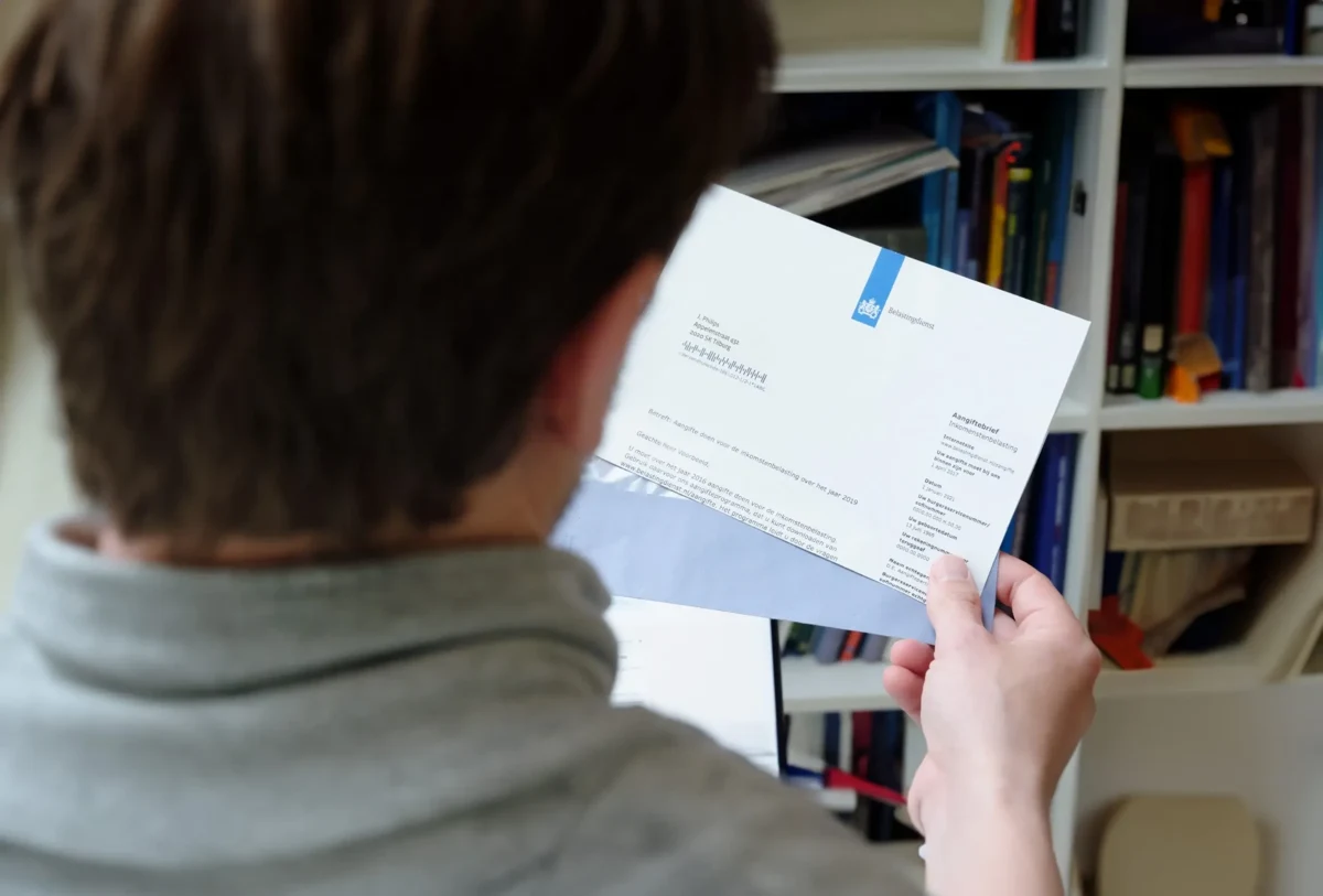 Man leest thuis een brief van de Belastingdienst