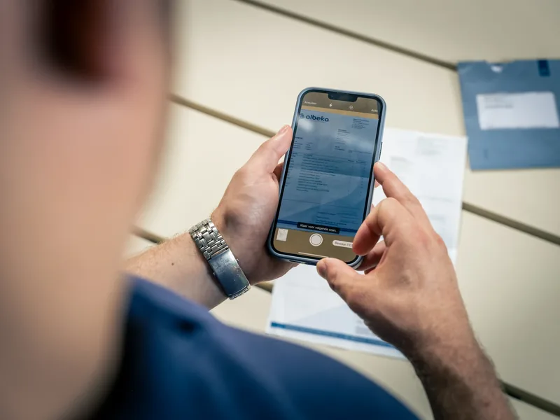 Een ondernemer fotografeert een factuur voor digitale aanlevering